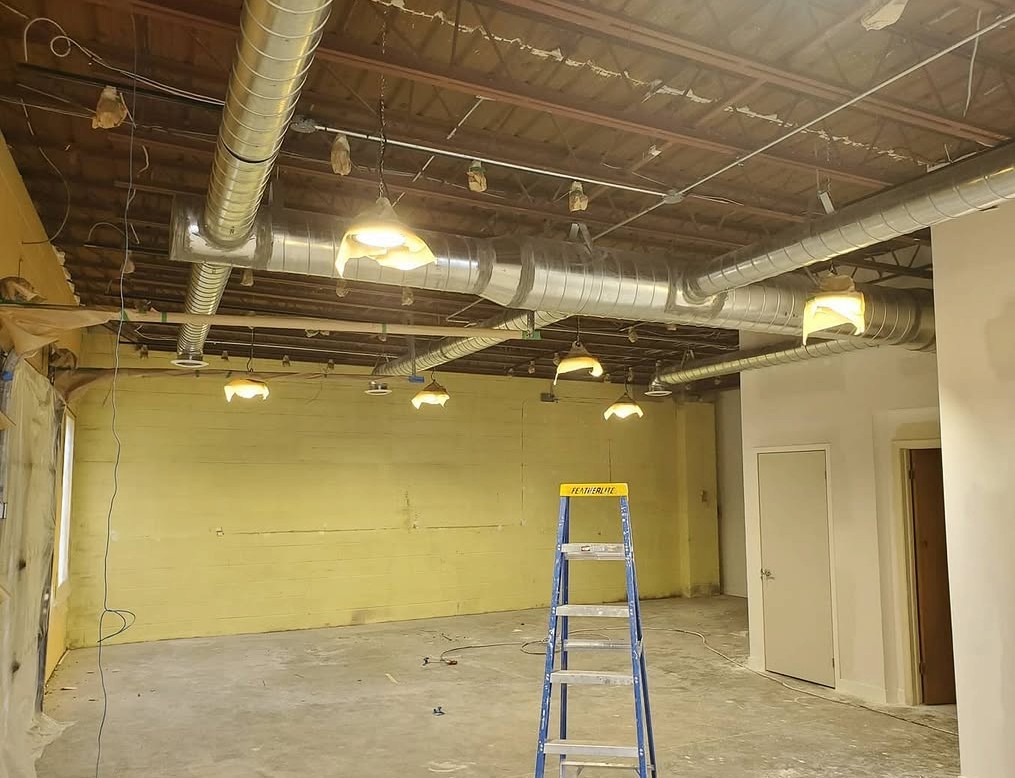 Unfinished commercial space with bare ductwork and yellow walls